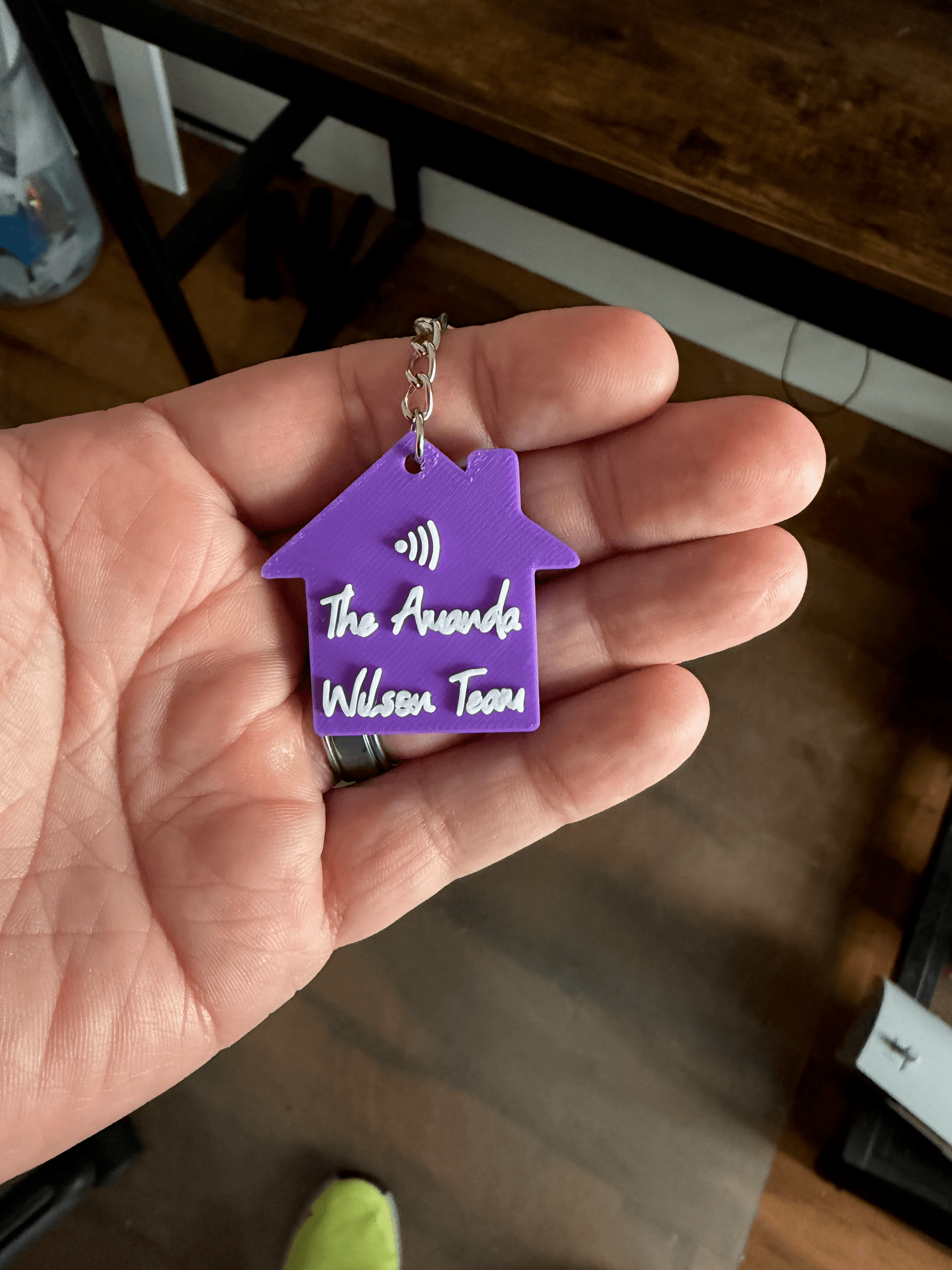 Custom purple house-shaped NFC keychain held in hand