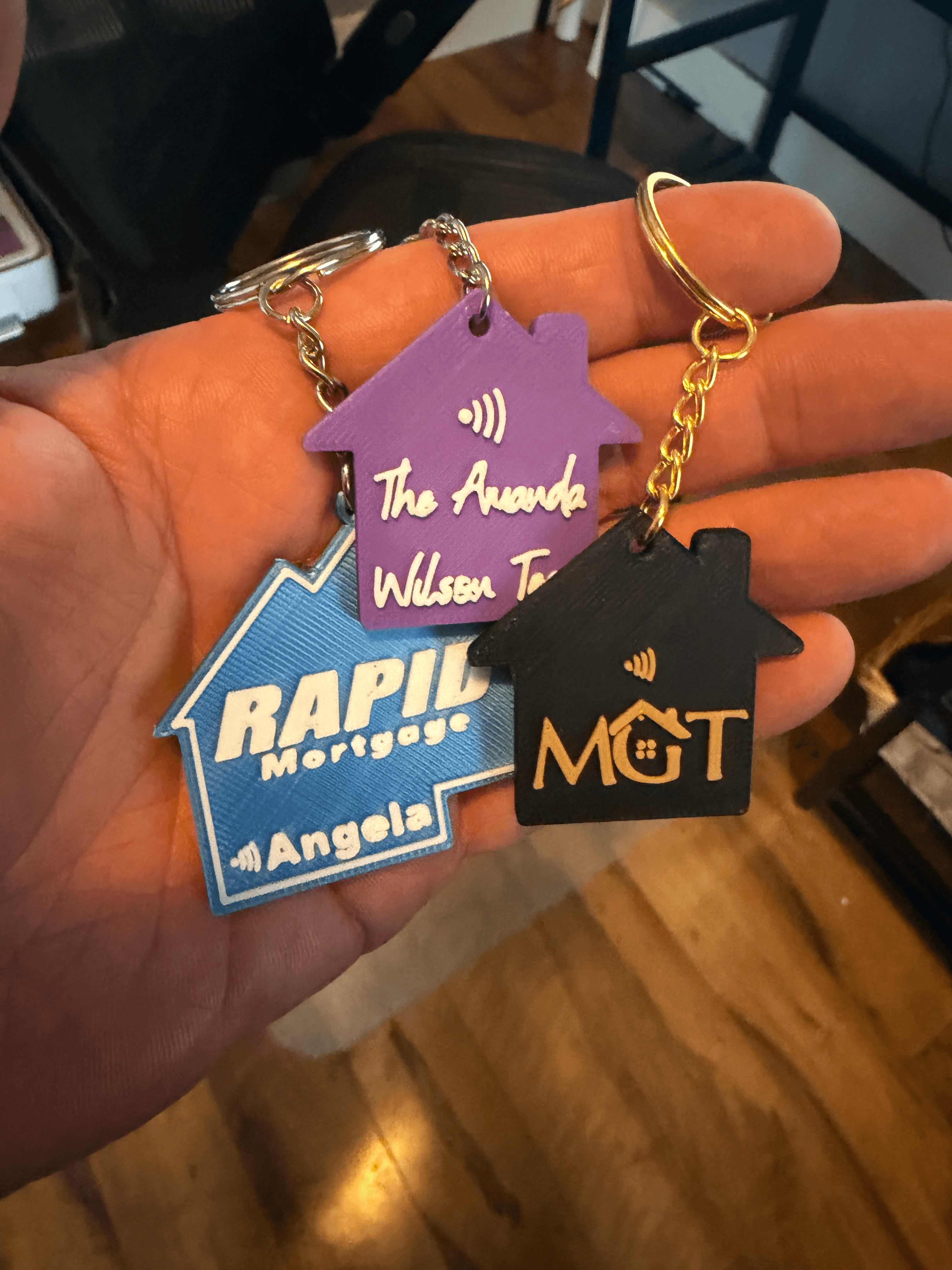 Three custom house-shaped NFC keychains in different brand colors